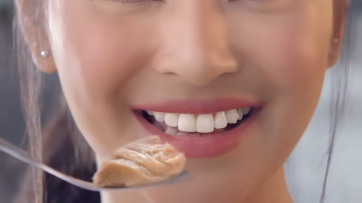 a woman eats canned tuna with a fork
